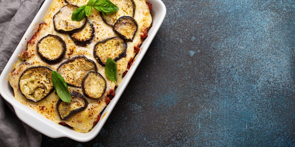 greek-mediterranean-dish-moussaka-with-baked-eggplants-ground-beef-white-ceramic-casserole-rustic-stone-background-from-traditional-dish-greece-space-text